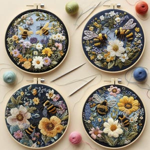 May include: Four embroidered hoops featuring bees and flowers. Each hoop has a dark blue background with colorful floral designs and detailed bee embroidery. The hoops are surrounded by wooden frames, with spools of thread and needles.