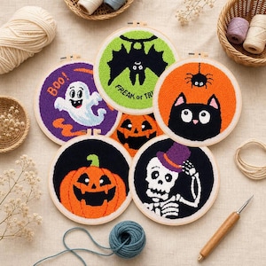 May include: Five circular punch needle embroidery hoops featuring Halloween designs: a white ghost on purple with the text Boo, a black bat on green with the text Freak, a black cat on orange, a jack-o'-lantern on black, and a skeleton in a hat.