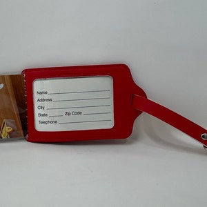 May include: Red luggage tag with a Mickey Mouse cartoon image on the front and a clear plastic window on the back with blank spaces for name, address, city, state, zip code, and telephone number.