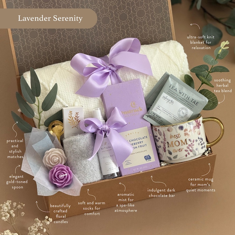 May include: A gift basket labeled "Lavender Serenity" contains a white knit blanket, purple ribbon, a floral mug, tea, chocolate, candles, socks, and an aromatic mist. The mug says "best MOM ever". The basket includes a gold-toned spoon and matches.