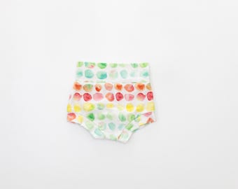 May include: White baby bloomers with a colorful watercolor dot pattern. The dots are in shades of green, blue, yellow, orange, and red.