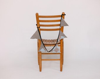May include: A wooden chair with a blue and gray fabric bunting draped over the back.
