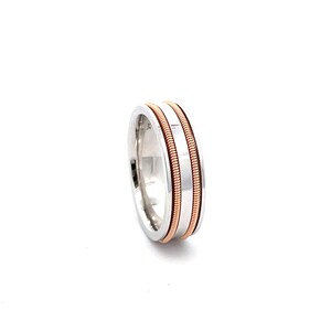 May include: A silver wedding band with two rose gold bands around the center.