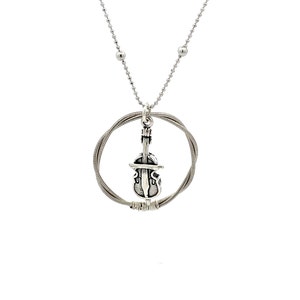 May include: A silver necklace with a silver circle pendant featuring a violin charm. The circle is made of guitar strings.