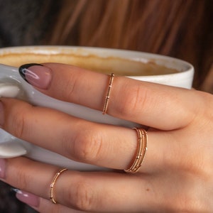 stacking duo guitar string rings on hand model holding coffee cup
