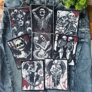 May include: A set of nine iron-on patches featuring various black and white illustrations of skeletons, skulls, and other gothic imagery. The patches are on a blue denim background.