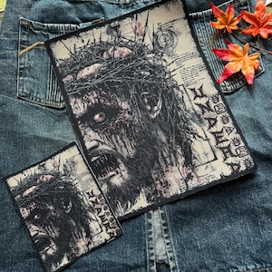 May include: Two black and white iron-on patches featuring a graphic of a bloody, crowned figure with the text "NAPALM DEATH" in red and black.