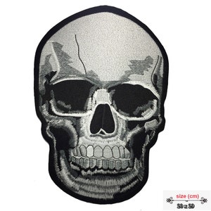 Könnte beinhalten: Ein großer, weißer gestickter Totenkopf-Patch mit schwarzen Augen und Zähnen. Der Patch misst 20 cm x 29 cm.