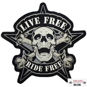 Könnte beinhalten: Schwarz-weißer, gestickter Aufnäher mit Totenkopf und gekreuzten Knochen. Der Aufnäher ist sternförmig und trägt den Text "LIVE FREE RIDE FREE". Größe: 24 x 24 cm.