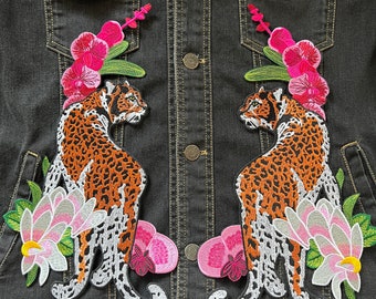 May include: A black denim jacket with two embroidered patches. Each patch features a leopard with pink flowers and green leaves.
