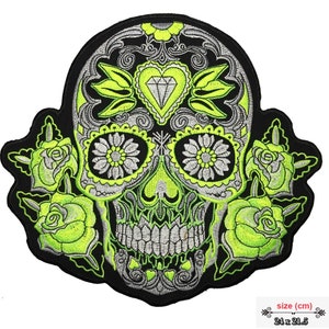 Könnte beinhalten: Grün und silber gestickter Totenkopf mit floralen Details und einem Diamanten auf der Stirn. Der Totenkopf ist von drei grünen Rosen umgeben. Der Patch ist 24 x 21,5 cm groß.