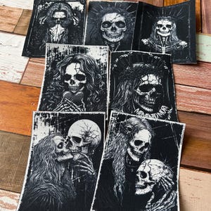 Könnte beinhalten: Set mit 8 schwarzen und weißen Bügelbildern mit verschiedenen Totenkopfmotiven. Die Totenköpfe sind in einem gotischen Stil mit aufwendigen Details dargestellt. Einige der Totenköpfe tragen Kronen oder halten Herzen in ihren Händen.