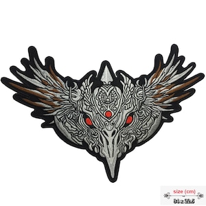 May include: A silver and brown embroidered patch with a detailed design of a bird's head with wings. The bird's eyes are red and the patch is 14 inches by 9 inches.