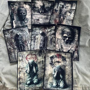 Può includere: Una collezione di stampe artistiche gotiche con immagini oscure. Le stampe raffigurano teschi, figure scheletriche e figure inginocchiate con il volto coperto. L'opera è realizzata in tonalità di grigio, nero e rosso, con texture di carta invecchiata e simboli occulti.