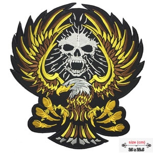 May include: Embroidered patch featuring a black eagle with gold and brown wings, holding a white skull with a black ace of spades in the background. The patch measures 25 x 22.5 cm.