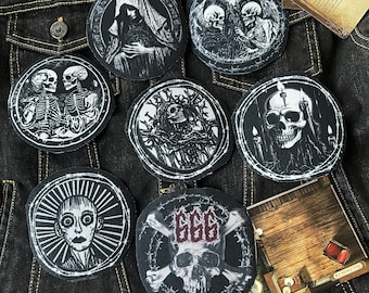 Könnte beinhalten: Sieben gestickte Patches in Schwarz und Weiß mit verschiedenen Designs, darunter Schädel, Skelette und eine Kapuzenfigur. Die Patches sind auf eine dunkelblaue Jeansjacke genäht.