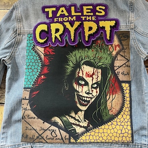 May include: A denim jacket with a Tales From The Crypt patch sewn on the front. The patch is purple with yellow lettering. The jacket also has a graphic patch of a woman with green hair and blood on her face.