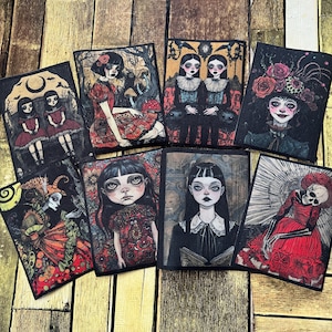 May include: A collection of eight rectangular art prints featuring gothic-style illustrations. The prints showcase portraits of women and figures with dark, expressive eyes, dressed in vintage clothing, and surrounded by surreal elements. The color palette includes reds, blacks, and muted tones.