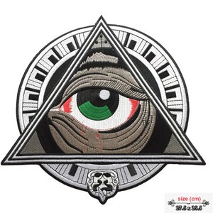 Könnte beinhalten: Gestickter Aufnäher mit einem detaillierten Auge in einem Dreieck, umgeben von einem kreisförmigen Design. Das Auge hat eine grüne Iris, rote Adern und eine Träne. Der Aufnäher ist in Grau-, Schwarz- und Weißtönen gehalten und misst 27,5 x 26,5 cm.