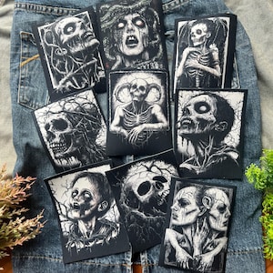 May include: Nine black and white iron-on patches featuring various spooky and gothic imagery. The patches feature skulls, skeletons, and other creepy creatures.