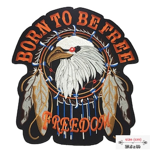 Könnte beinhalten: Gestickter Aufnäher mit einem Adlerkopf in einem Traumfänger-Design. Der Aufnäher ist schwarz mit orangefarbenen, weißen, braunen und blauen Details. Der Text lautet "BORN TO BE FREE" und "FREEDOM". Der Aufnäher misst 27,5 x 30 cm.