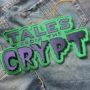 May include: Green and purple embroidered patch with the text "Tales from the Crypt" in a dripping font.