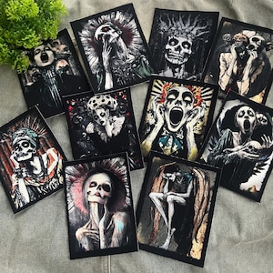 May include: A collection of rectangular art prints featuring gothic and macabre illustrations. The images depict skeletal figures with expressive faces, some with halos or crowns, in shades of black, white, and red. The artwork evokes themes of mortality and the supernatural.