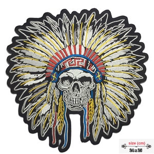 May include: Embroidered iron-on patch featuring a skull wearing a colorful Native American headdress with white feathers. The patch is 24 inches by 25 inches.