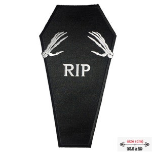 Könnte beinhalten: Schwarzer Sargförmiger Aufnäher mit weißen, gestickten Skeletthänden. Der Aufnäher hat die Buchstaben "RIP" in Weiß gestickt. Der Aufnäher misst 16,5 x 29 cm.