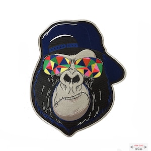 Può includere: Toppa ricamata di un gorilla con un berretto da baseball blu e occhiali da sole colorati. Il gorilla ha un'espressione seria.