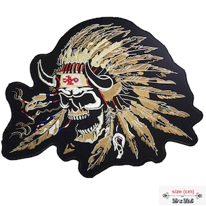 May include: Black embroidered patch with a white skull wearing a gold and brown feathered headdress. The skull has horns and a red, white, and blue band around its head. The patch is 29 x 22.5 cm.