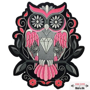 Könnte beinhalten: Rosa und graue gestickte Bügelapplikation mit einer Eule mit einem Diamanten und Rosen. Die Eule sitzt auf einem Ast mit Blättern und Blumen. Die Applikation ist 22,5 cm x 24 cm groß.