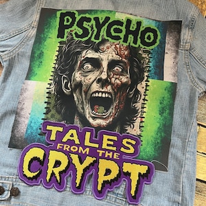 Può includere: Una giacca di jeans con una toppa viola e gialla che dice "Tales From The Crypt" e una toppa verde e blu con un viso di zombie e la parola "Psycho".