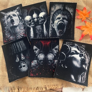 Könnte beinhalten: Sechs schwarz-weiße Gothic-Kunstaufnäher mit makabren Bildern. Die Aufnäher zeigen Schädel, schreiende Gesichter und Figuren mit dunklen Themen. Die Kunstwerke sind detailliert und illustrativ und konzentrieren sich auf Horror und Okkultismus.
