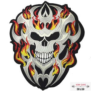 May include: A white skull with a tribal design and flames in red and yellow. The patch is 25 x 29 cm.