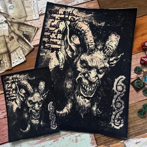 May include: Two black fabric patches with a white and black illustration of a horned demon with a menacing expression. The text "666" is visible on the right patch.