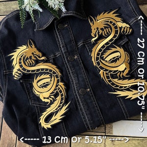 Peut inclure: Deux patchs brodés dorés de dragons à repasser sur une veste en jean noire. Les patchs mesurent 27 cm de haut et 13 cm de large.