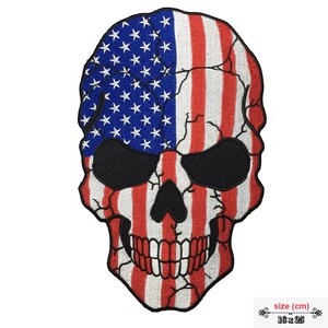May include: Embroidered patch of a skull with the American flag design. The skull is red, white, and blue with a cracked effect. The patch is 16 cm by 25 cm.