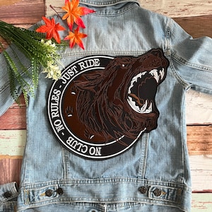 May include: A brown and black embroidered patch with a snarling wolf head and the text "NO CLUB - NO RULES - JUST RIDE".