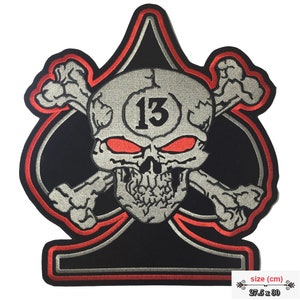 Könnte beinhalten: Schwarzer und roter gestickter Patch mit einem Totenkopf mit gekreuzten Knochen und der Zahl 13 in einem Kreis. Der Schädel hat rote Augen und ist auf eine schwarze Pikform gesetzt. Der Patch misst 27,5 cm x 30 cm.