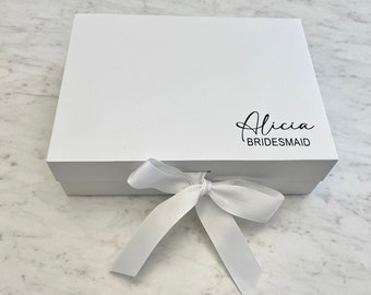 May include: White gift box with a white satin ribbon tied in a bow. The box has the name "Alicia Bridesmaid" printed on the top.