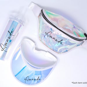 Könnte beinhalten: Ein Set aus drei regenbogenfarbenen Accessoires mit dem Namen "Amanda" auf jedem Artikel. Das Set beinhaltet eine Bauchtasche, ein Visier und einen Becher mit Strohhalm.