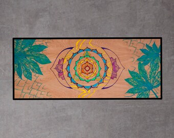 Può includere: Un tappetino da yoga in legno con un design a mandala colorato e motivi di foglie verdi sui lati. Il mandala presenta un cerchio centrale con un triangolo all'interno, circondato da un anello di petali in tonalità di arancione, giallo, verde e blu.