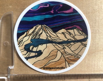 Può includere: Adesivo rotondo raffigurante un paesaggio montano con un fiume e un cielo colorato. L'adesivo ha un bordo bianco e il testo "@littlesurstudio". L'adesivo ha un diametro di circa 5 cm.