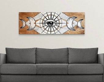 Può includere: Un'opera d'arte murale in legno con un'illustrazione in bianco e nero di un occhio circondato da un'esplosione di sole e lune crescenti. Lo sfondo è in legno marrone chiaro.