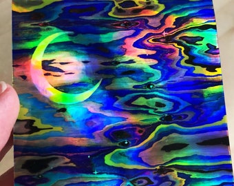Può includere: Un adesivo olografico con un design a forma di luna crescente. L'adesivo presenta un motivo astratto a spirale in tonalità di blu, verde, giallo e rosa.