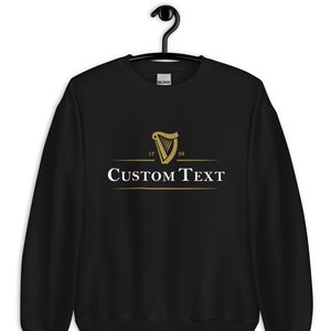 May include: Black sweatshirt with a gold harp logo and the text "CUSTOM TEXT" underneath. The harp logo has the numbers 17 and 59 on either side.