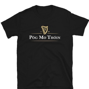 May include: Black t-shirt with a gold harp logo and the text "Póg Mo Thóin" in white.