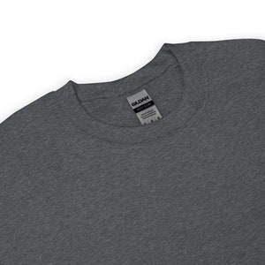 May include: A dark gray t-shirt with a Gildan Heavy Blend label attached to the neck.