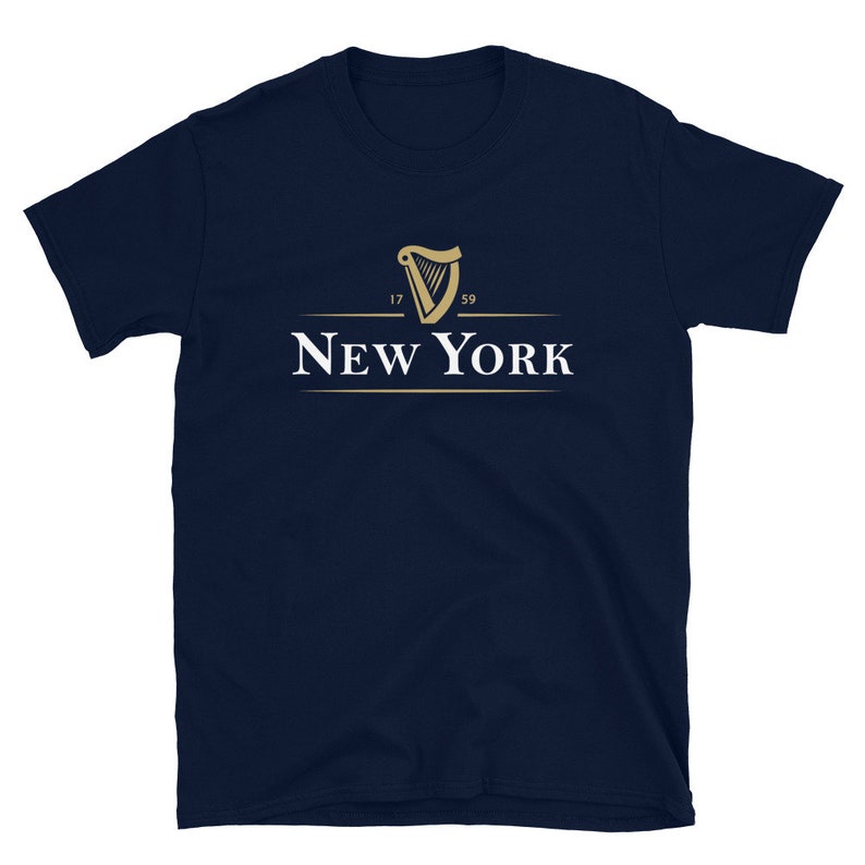 May include: A navy blue t-shirt featuring a gold harp logo and the text "NEW YORK" underneath. The harp logo has the numbers "17" and "59" on either side.
